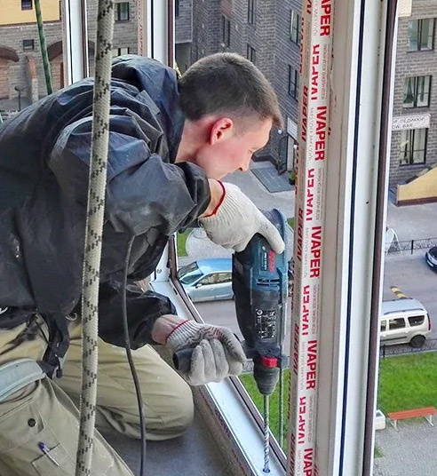 Специалист занимается остеклением балкона